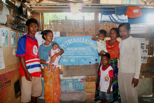 Pak Ishaka Mansyur dan keluarga dengan latar papan nama yang menjadi kebanggaannya